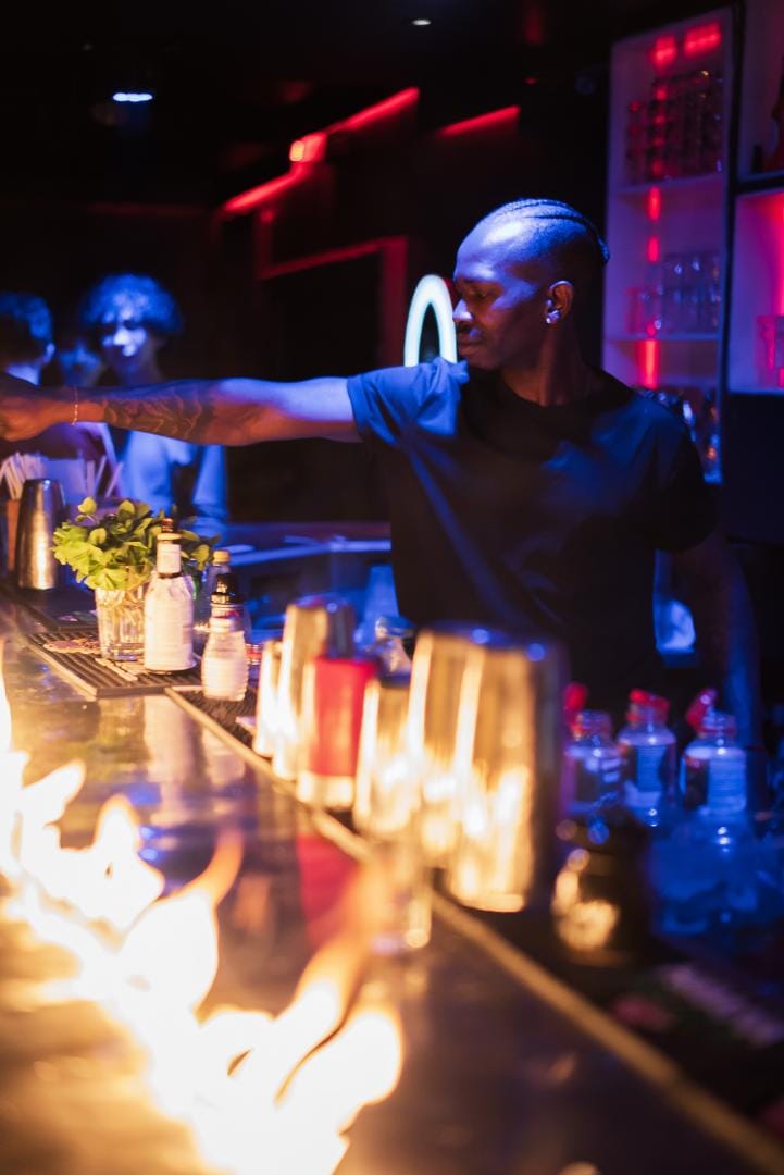 Barman servant derrière un bar illuminé par des flammes