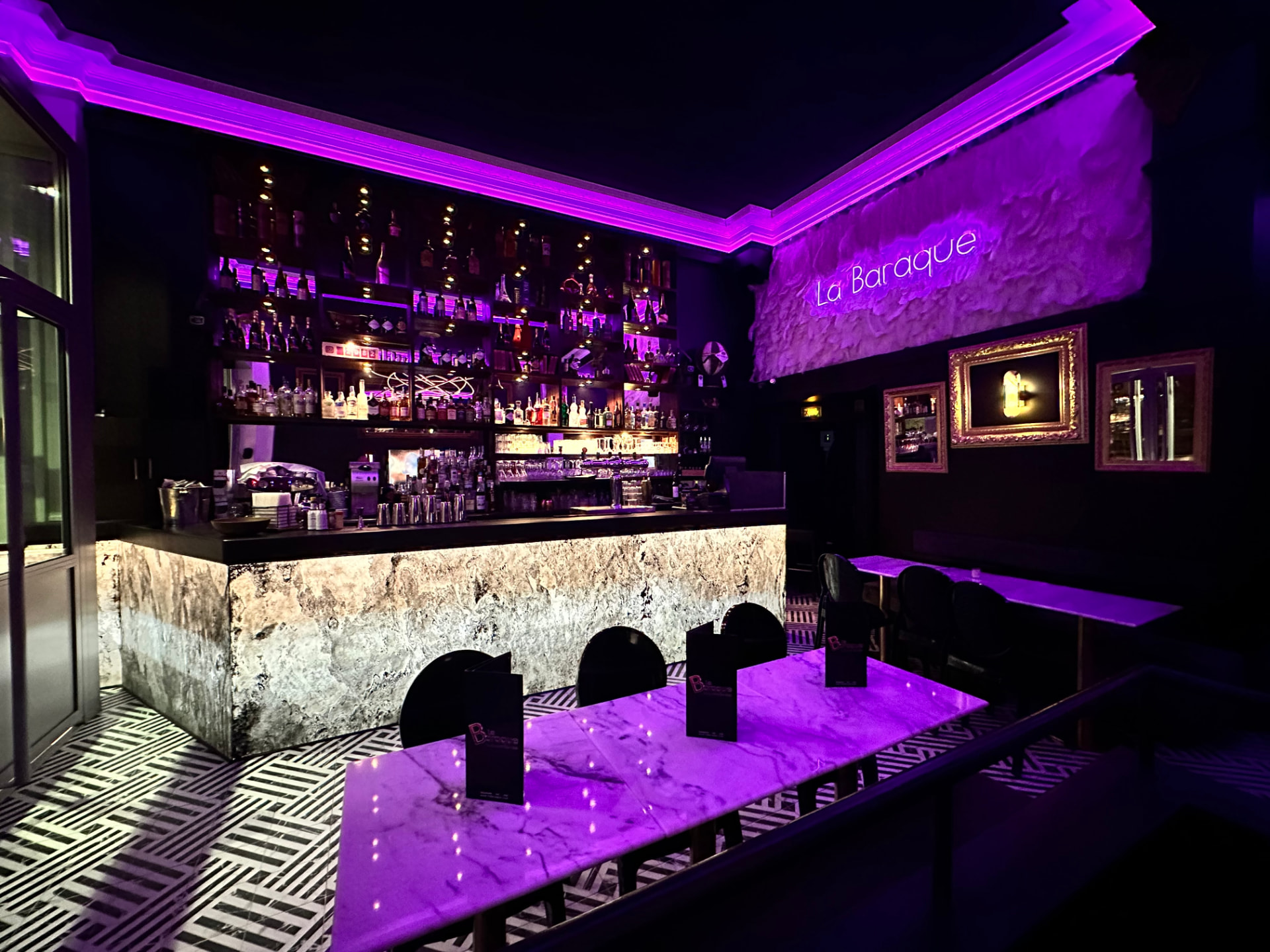 Le bar de La Baraque avec comptoir en marbre et néons